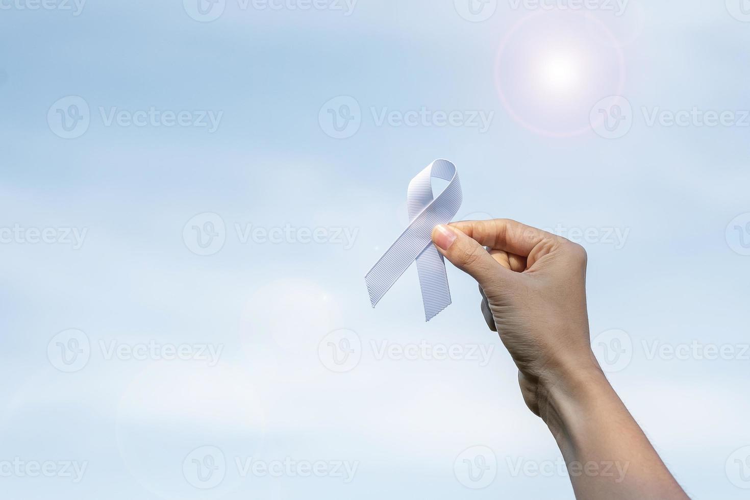 November Lung Cancer Awareness month, democracy and international peace day. Woman holding white Ribbon on sky background photo