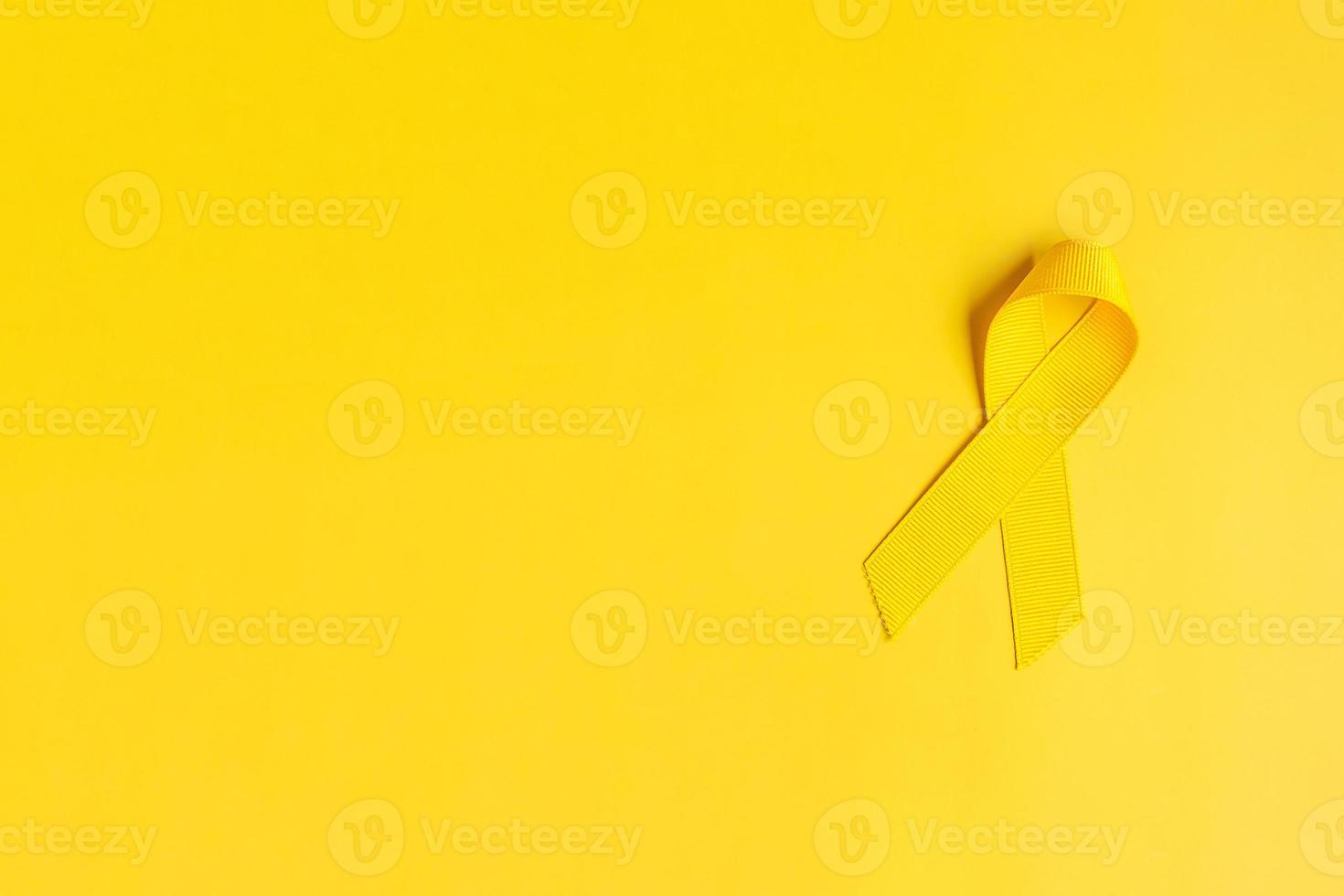 Yellow Ribbon on yellow background for supporting people living and illness. July Sarcoma cancer, Suicide prevention day, Childhood Cancer Awareness month concept photo