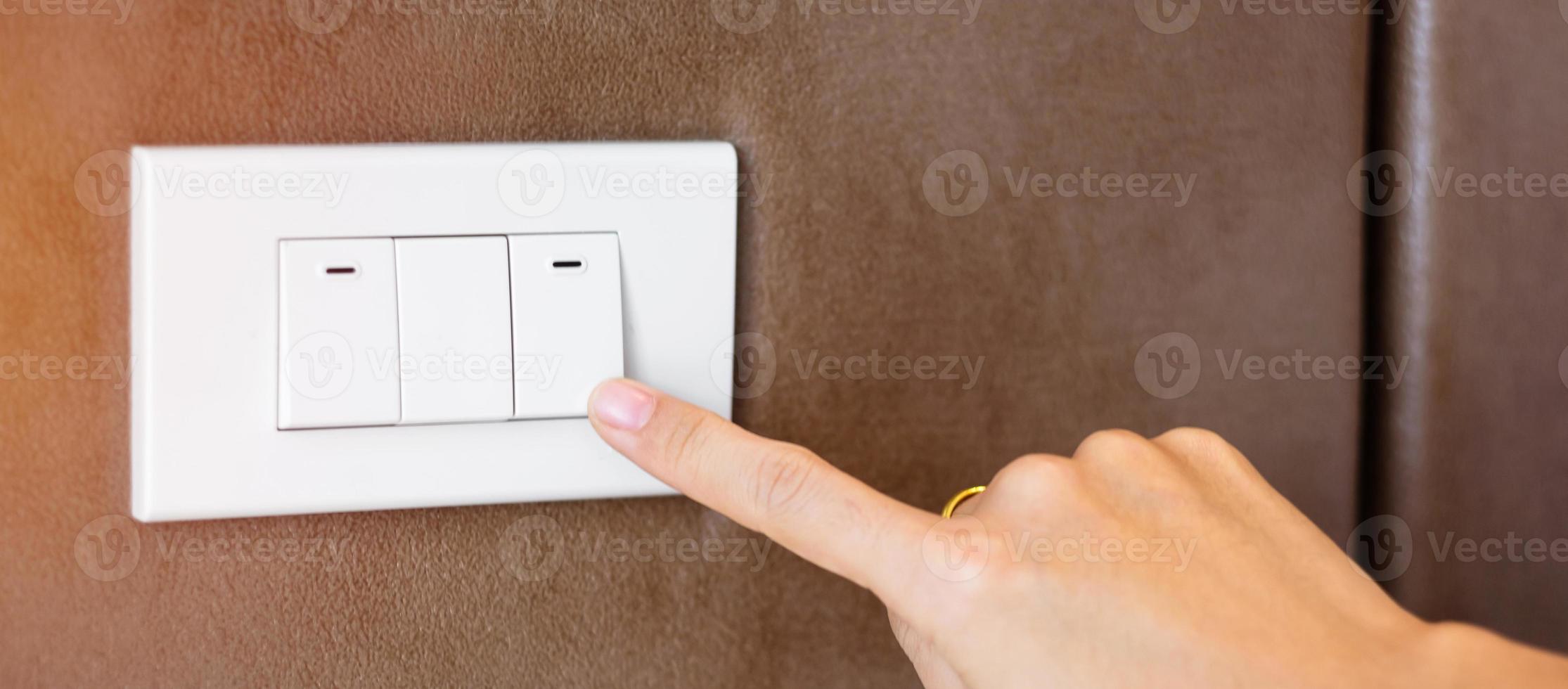 finger turn on or off on light switch on wall at home. Energy Saving, power, electrical and lifestyle concepts photo