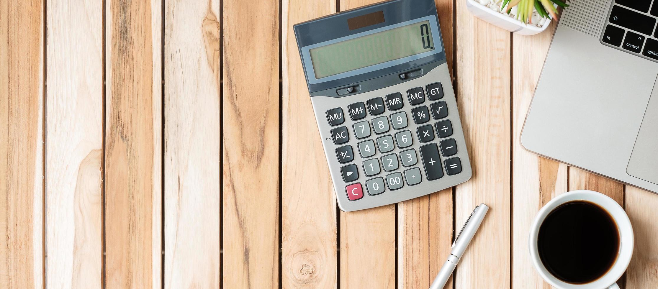 Top view Office desk with calculator, pen, computer laptop, plant pot and coffee cup on wood table background. workspace or home office with copy space for text concept photo