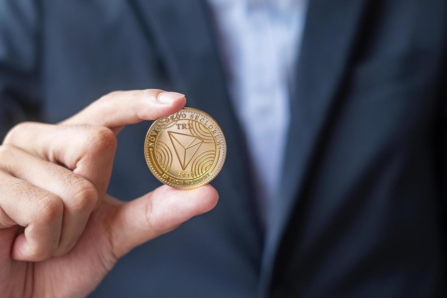 man hand holding gold Tron coin cryptocurrency, Crypto is Digital Money within the blockchain network, is exchanged using technology and online exchange. Decentralized Financial concept photo