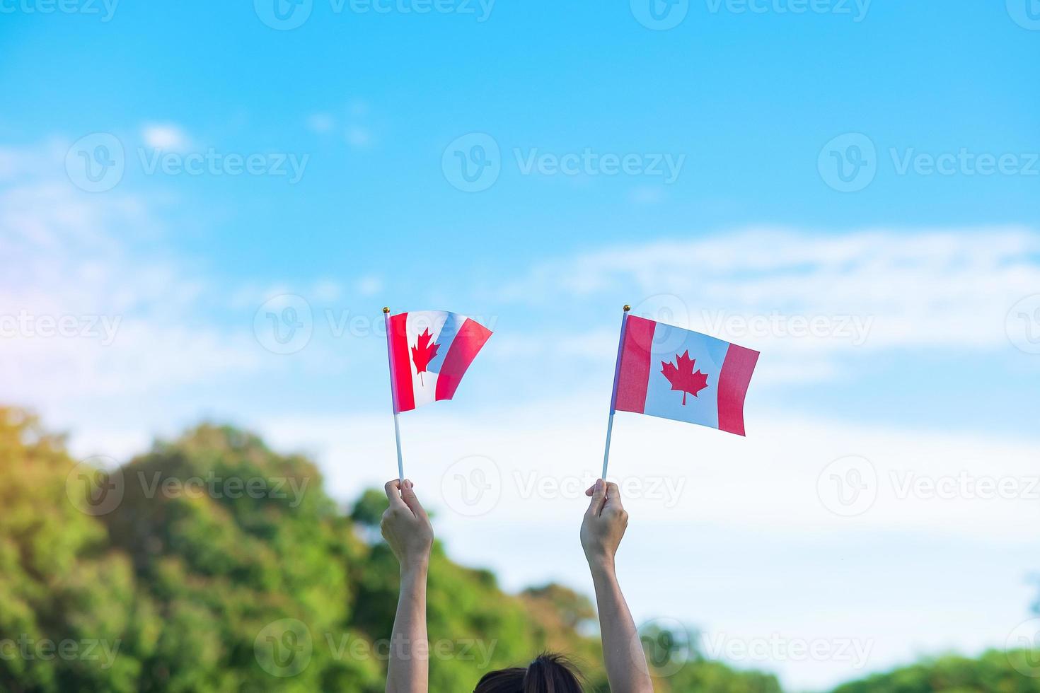 hand holding Canada flag on blue sky background. Canada Day  and happy celebration concepts photo