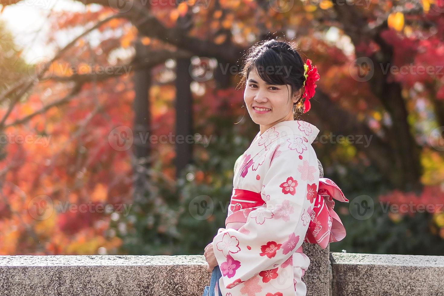 joven turista vistiendo kimono disfrutando con hojas coloridas en el templo kiyomizu dera, kyoto, japón. chica asiática con estilo de cabello en ropa tradicional japonesa en la temporada de follaje de otoño foto