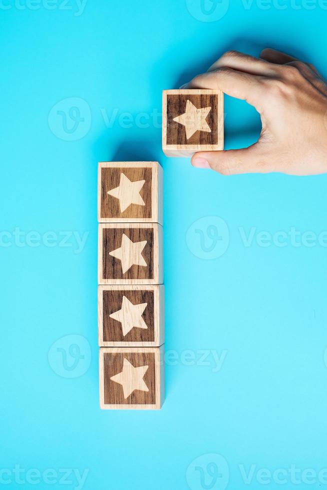 hand holding Star block on blue background. Customer choose rating for user reviews. Service rating, ranking, customer review, satisfaction, evaluation and feedback concept photo