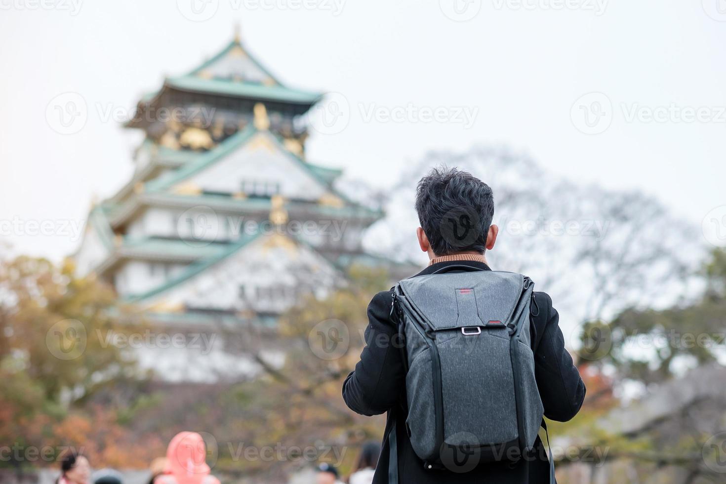 turista solo que viaja en el castillo de osaka en la temporada de otoño, visita de un viajero asiático en la ciudad de osaka, japón. vacaciones, destino y concepto de viaje foto