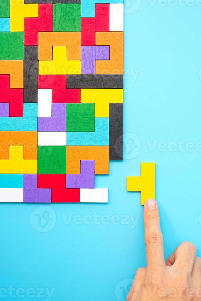 piezas de rompecabezas de madera de colores sobre fondo azul, bloque de forma geométrica. conceptos de pensamiento lógico, enigma, soluciones, racional, estrategia, día mundial de la lógica y educación foto