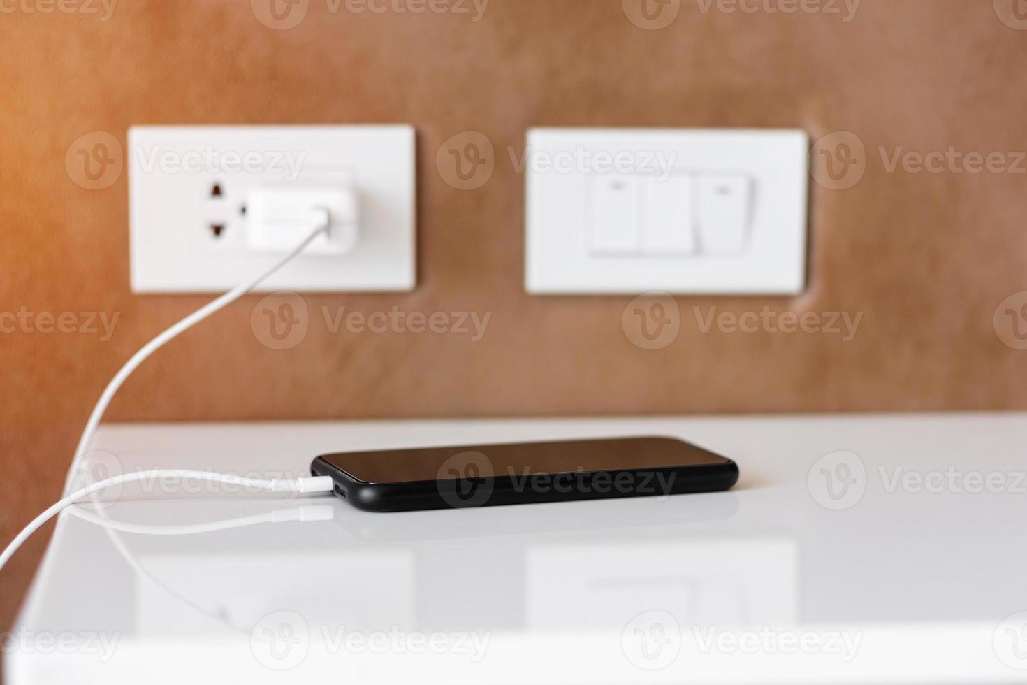 mobile smartphone charging battery on table at home or office. Technology, multiple sharing and recharge concepts photo