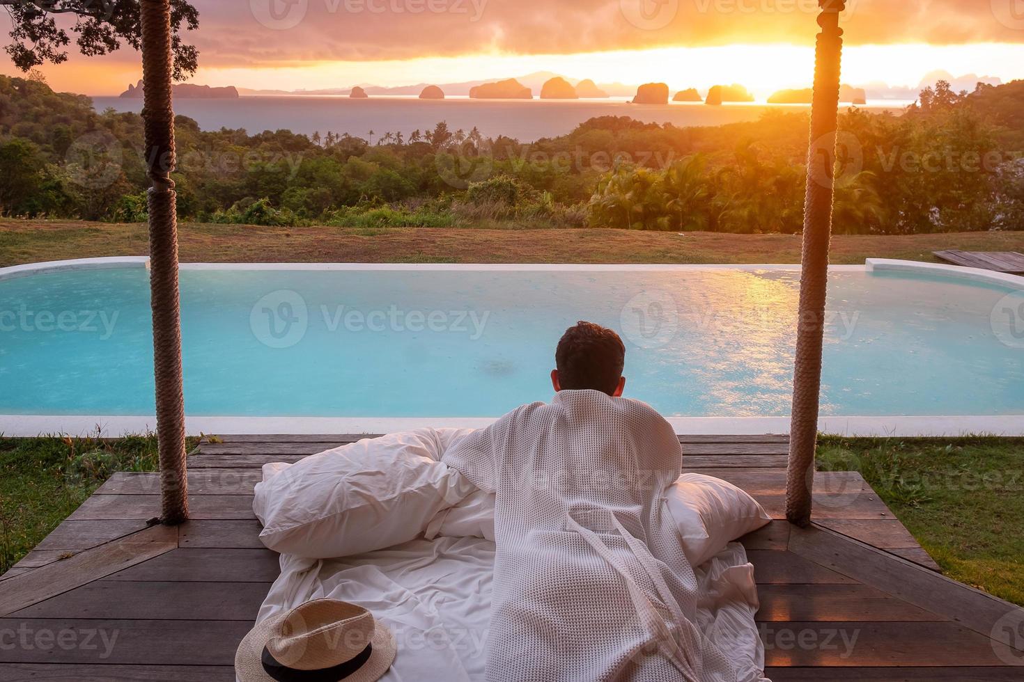 Happy man traveler enjoy Beautiful ocean view, Tourist relaxing in tropical luxury resort with swimming pool. Leisure, travel and summer vacation concept photo