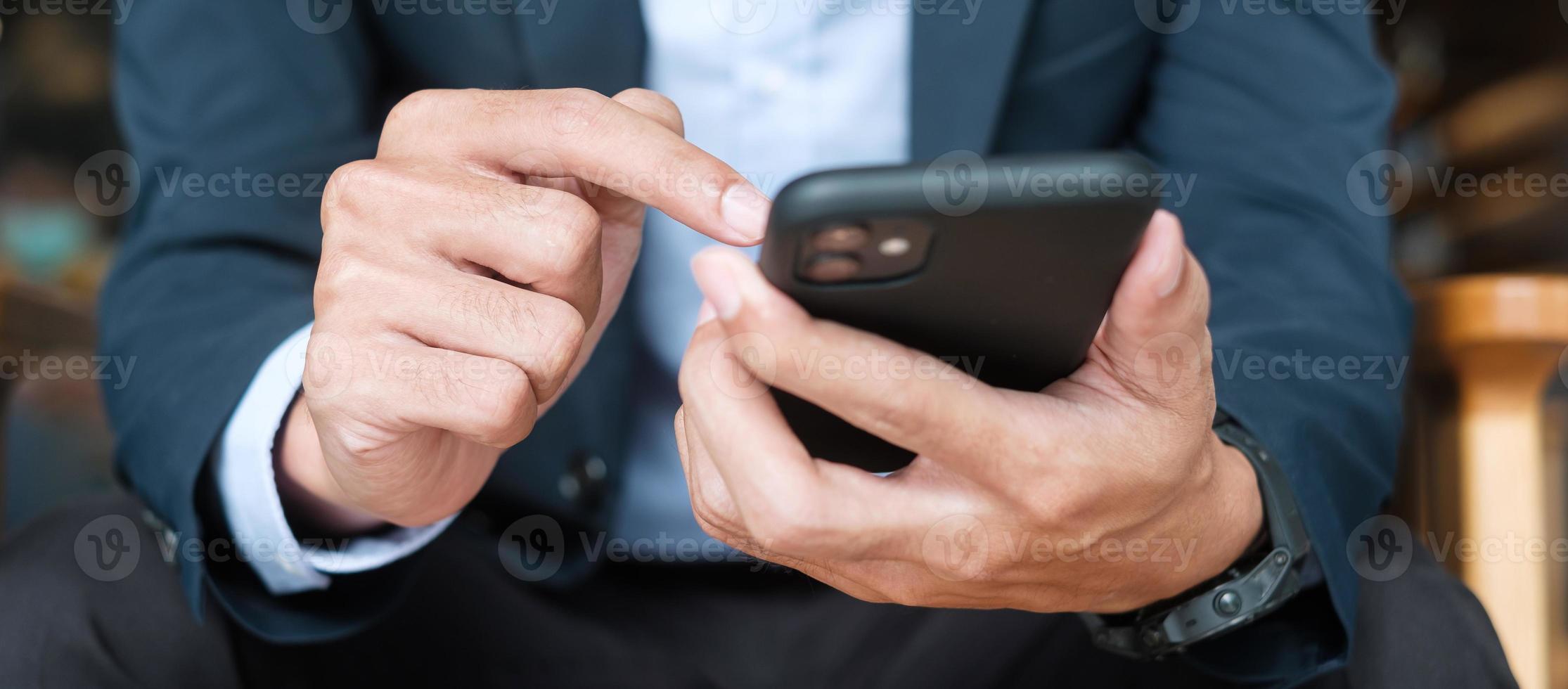 young Businessman in suit holding and using smartphone for sms messages, man typing touchscreen mobile phone in office or cafe. business, lifestyle, technology and Social media network concept photo