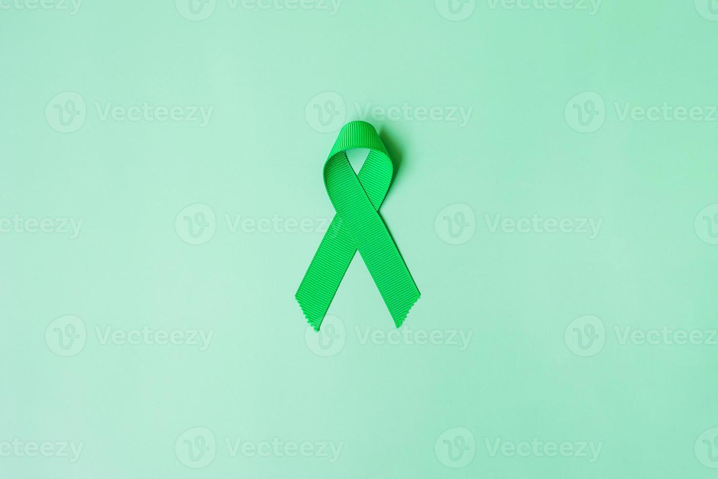 cinta verde sobre fondo de color verde para apoyar a las personas que viven y están enfermas. hígado, vesícula biliar, cáncer de vías biliares y concepto del mes de concientización sobre la donación de órganos foto