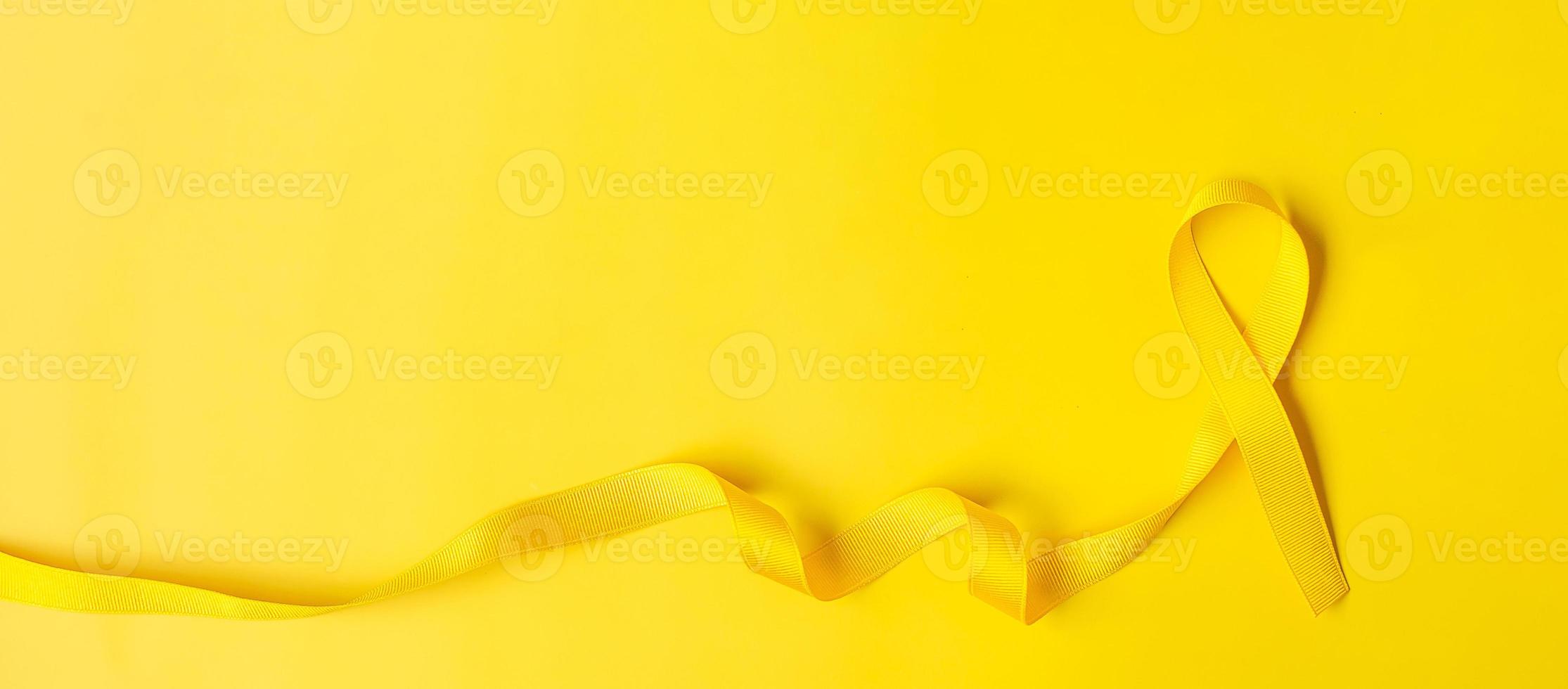 Yellow Ribbon on yellow background for supporting people living and illness. July Sarcoma cancer, Suicide prevention day, Childhood Cancer Awareness month concept photo