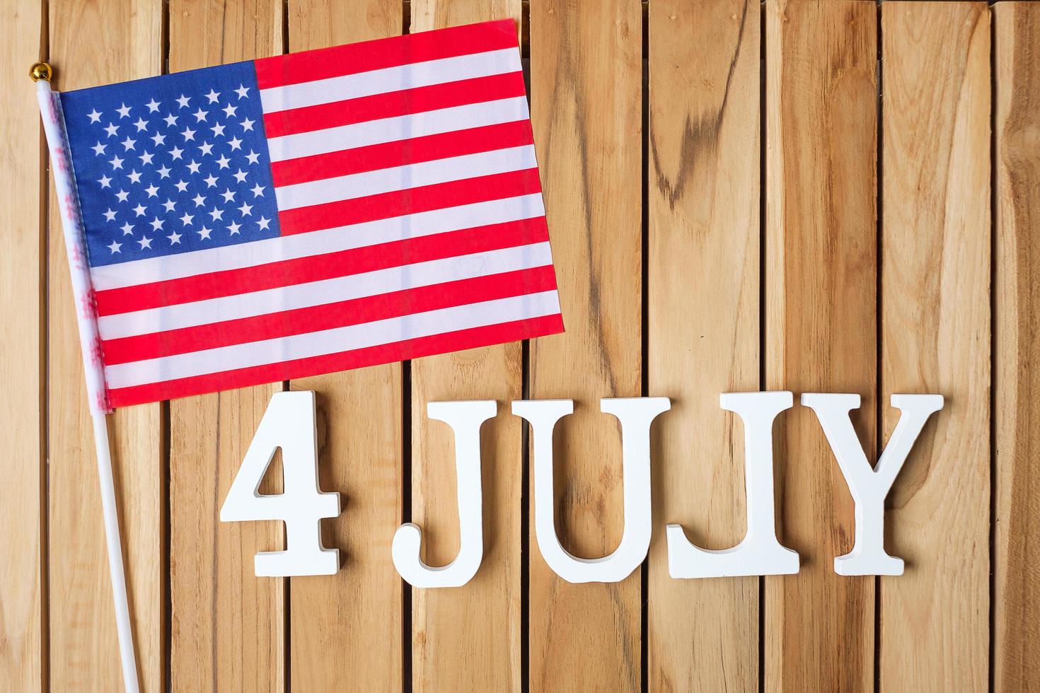 Fourth of July text and United States of America flag on wooden table background. USA holiday of Independence and celebration concepts photo