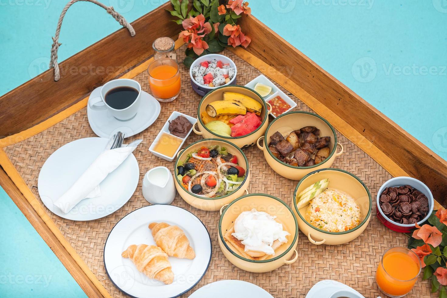 bandeja de desayuno flotante en la piscina del hotel de lujo o villa tropical, frutas, croissant, café y jugo de naranja. verano exótico, relajación, viajes tropicales y concepto de vacaciones foto