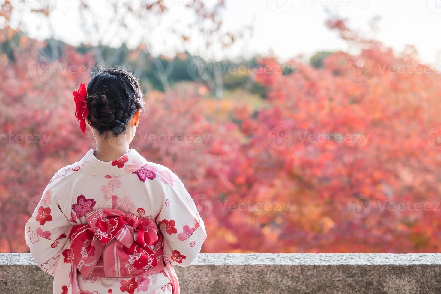 joven turista vistiendo kimono disfrutando con hojas coloridas en el templo kiyomizu dera, kyoto, japón. chica asiática con estilo de cabello en ropa tradicional japonesa en la temporada de follaje de otoño foto