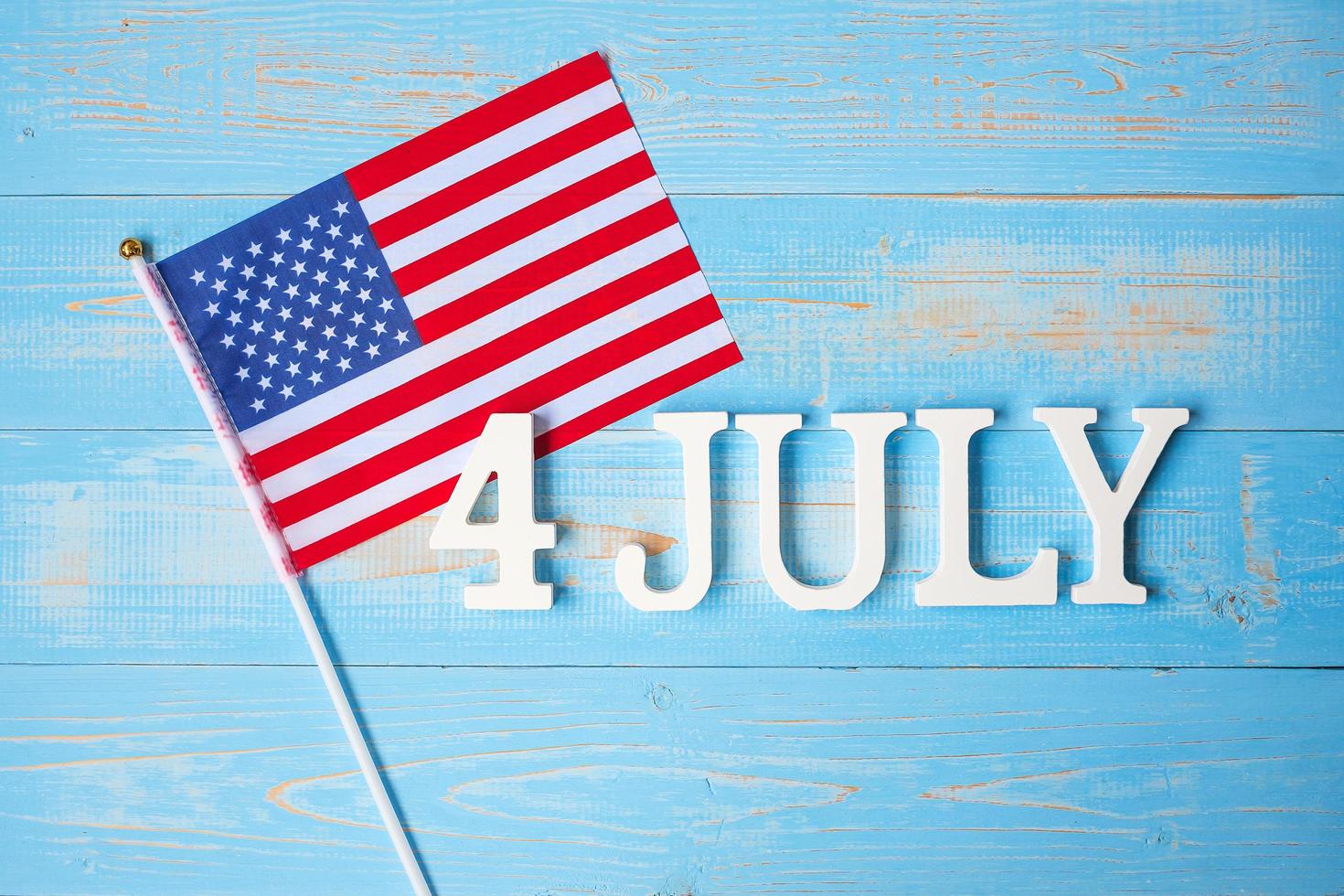 Fourth of July text and United States of America flag on wooden table background. USA holiday of Independence and celebration concepts photo