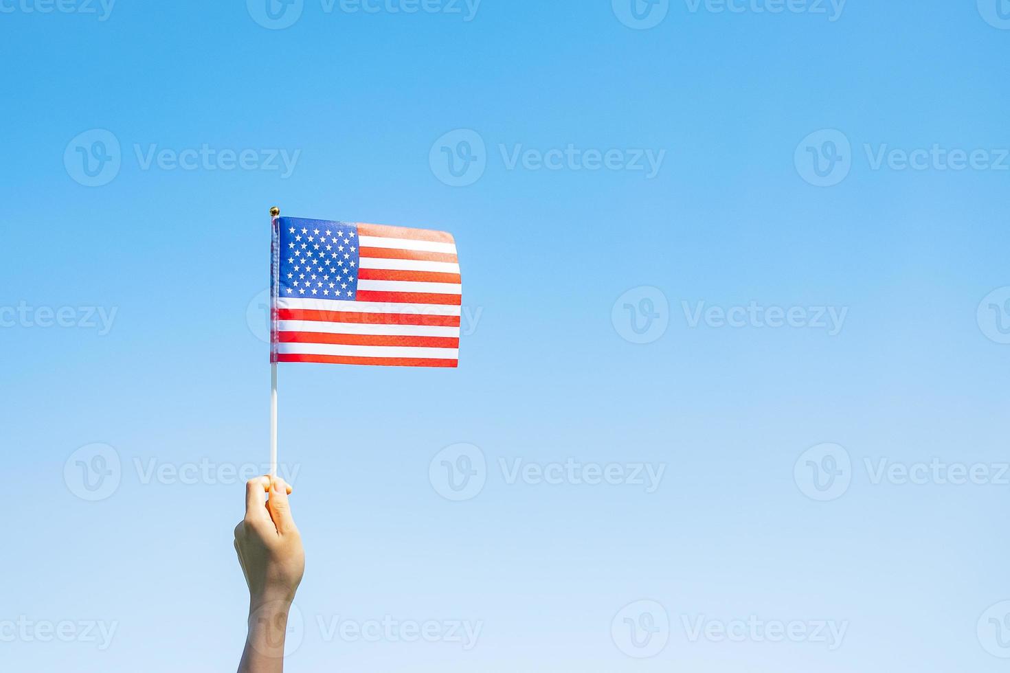 hand holding United States of America flag on blue sky background. USA holiday of Veterans, Memorial, Independence  and Labor Day concept photo