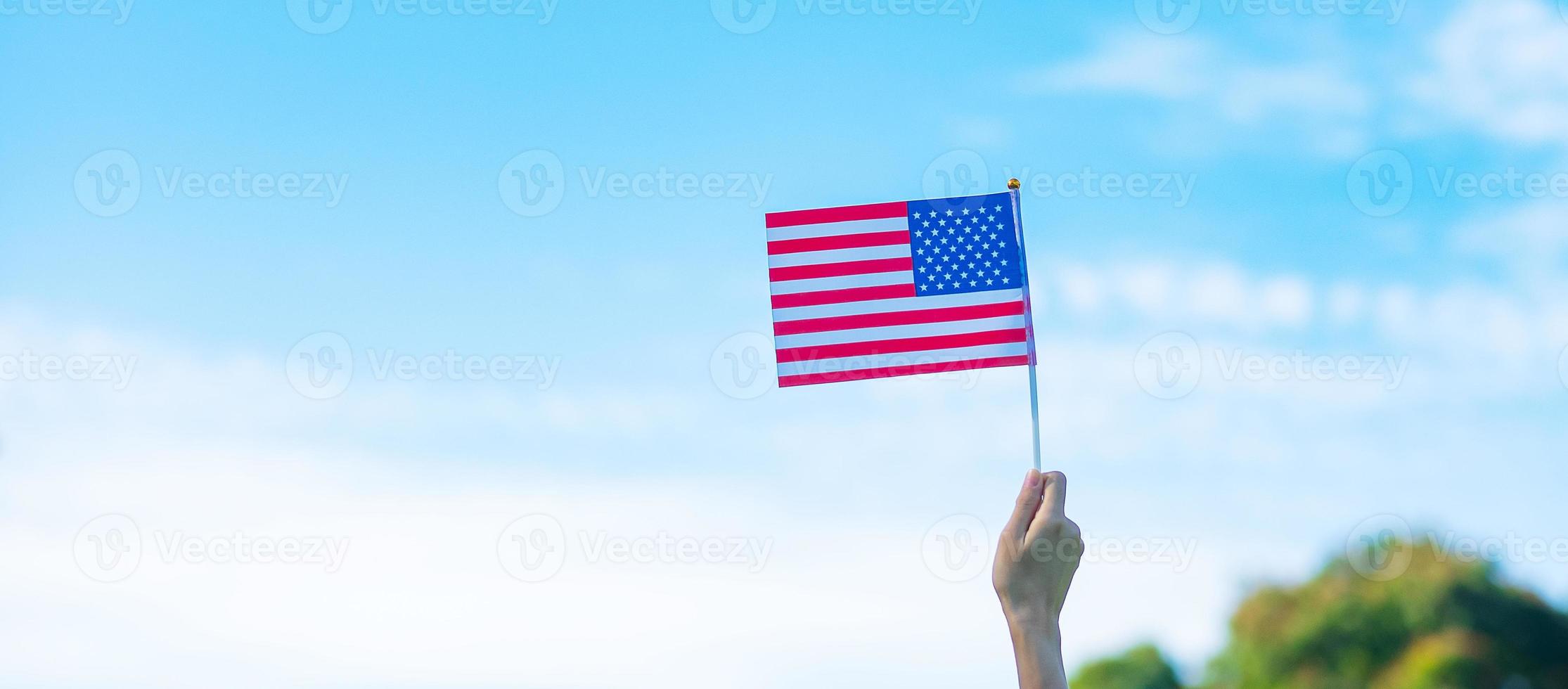 hand holding United States of America flag on blue sky background. USA holiday of Veterans, Memorial, Independence and Labor Day concept photo