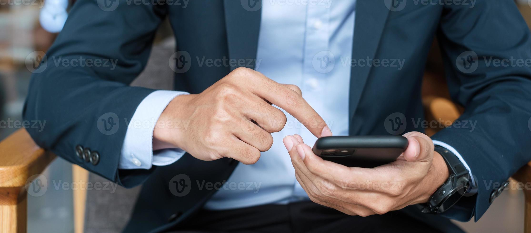 young Businessman in suit holding and using smartphone for sms messages, man typing touchscreen mobile phone in office or cafe. business, lifestyle, technology and Social media network concept photo