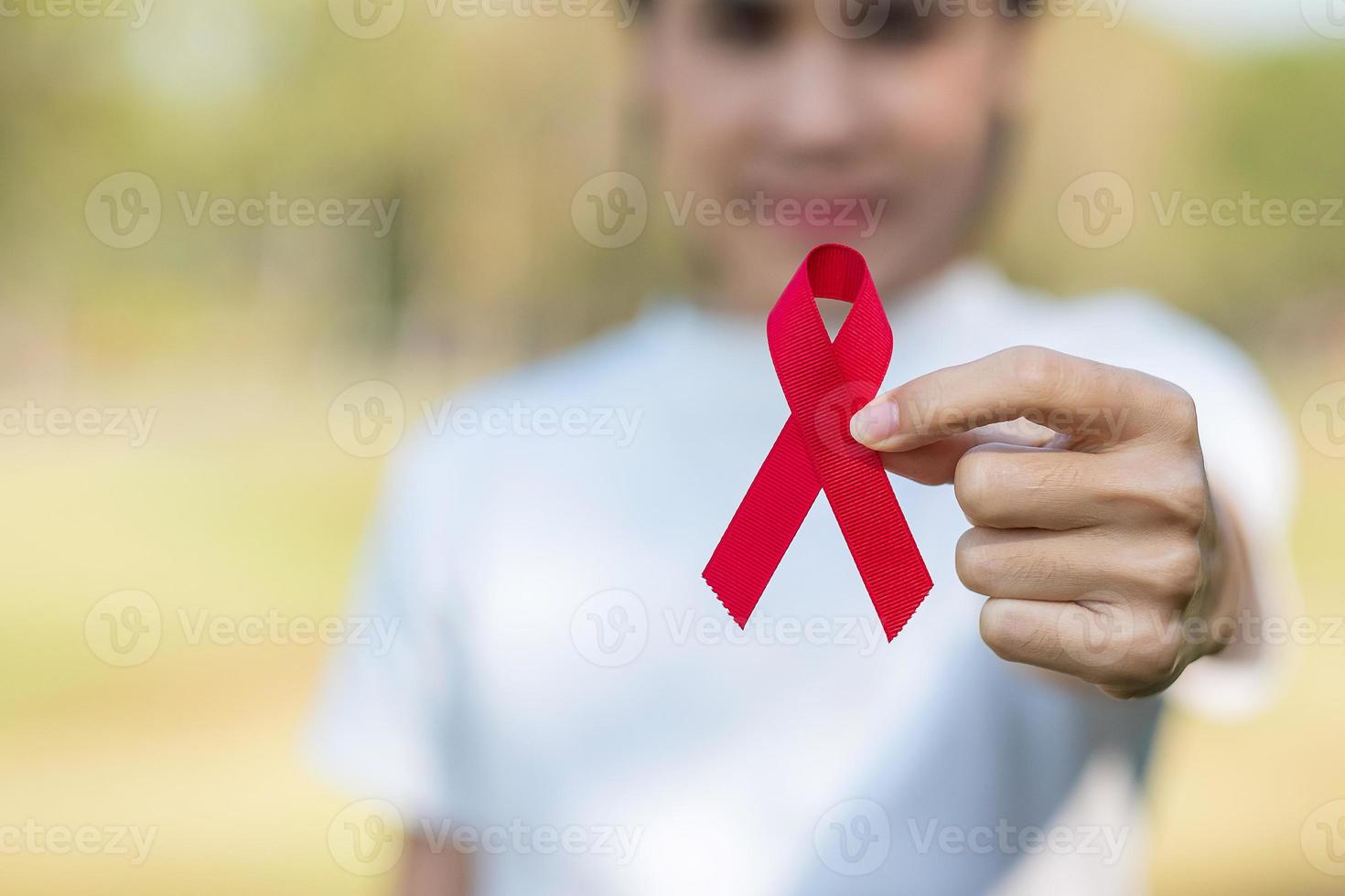 mano con cinta roja para apoyar a las personas que viven y están enfermas. concepto de salud y sexo seguro. diciembre día mundial del sida y mes de concientización sobre el cáncer de mieloma múltiple foto