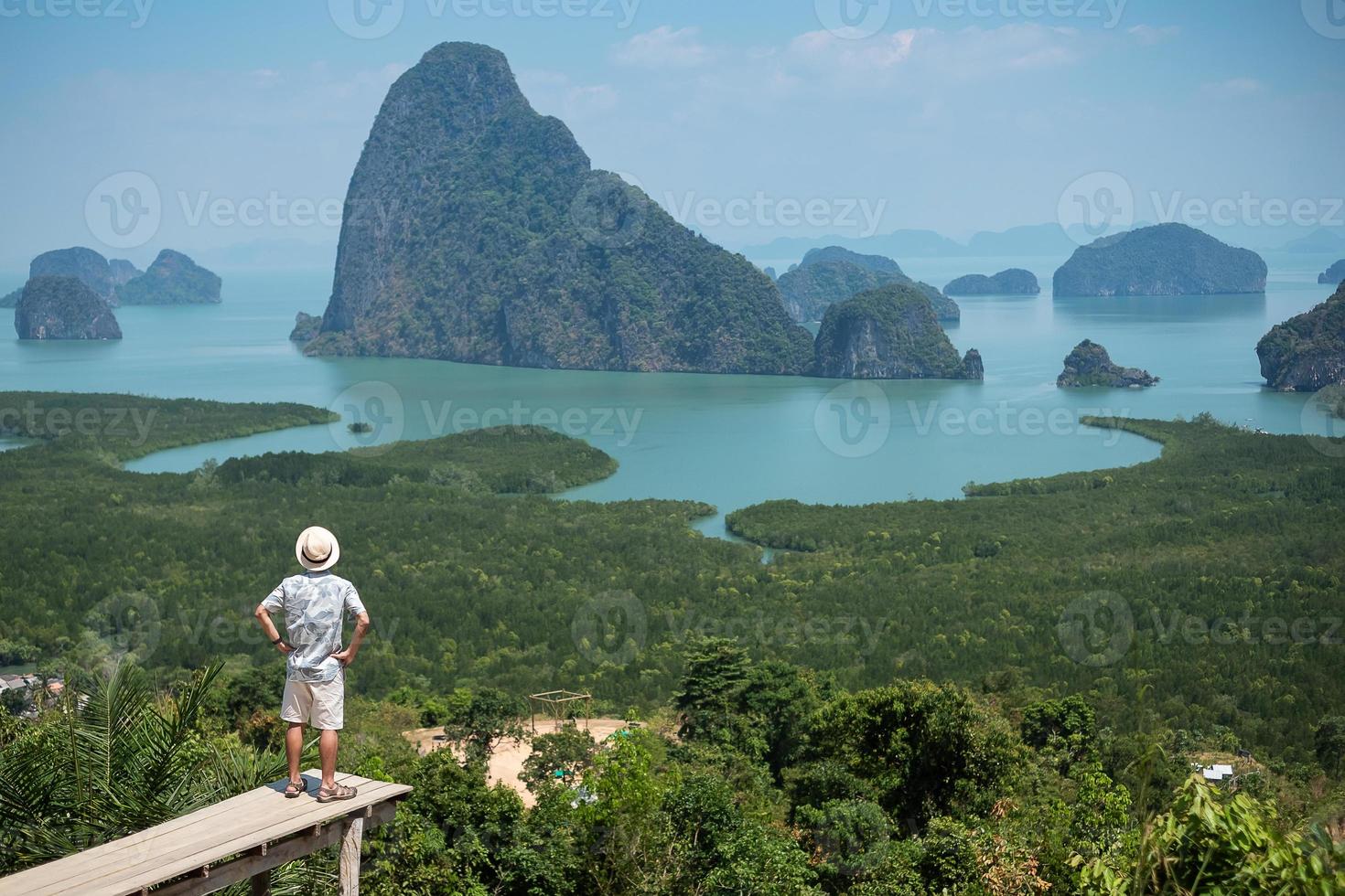 hombre viajero feliz disfruta del punto de vista de la bahía de phang nga, turista solo de pie y relajándose en samet nang she, cerca de phuket en el sur de tailandia. concepto de viaje, viaje y vacaciones de verano del sudeste asiático foto