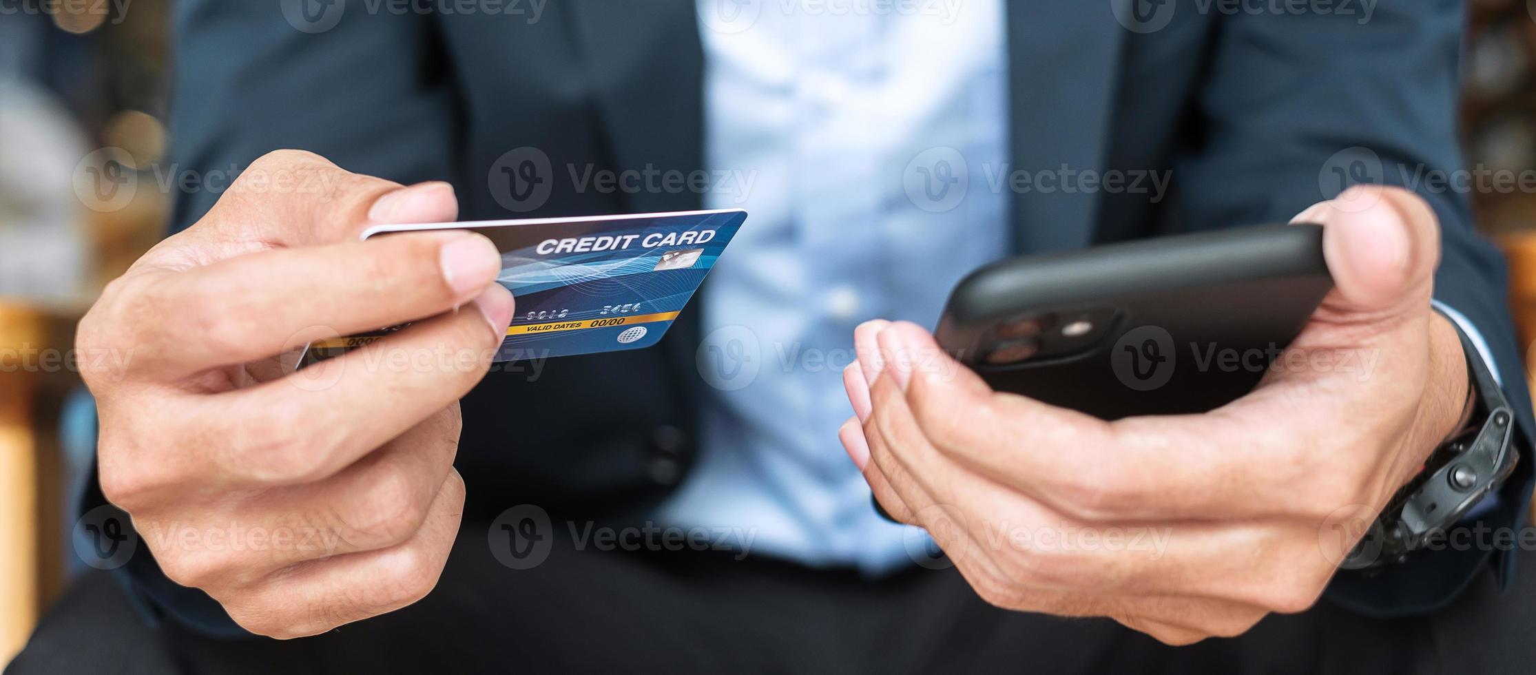 Businessman in suit holding credit card and using touchscreen smartphone for online shopping while making orders in the cafe or office .business, technology, ecommerce and online payment concept photo