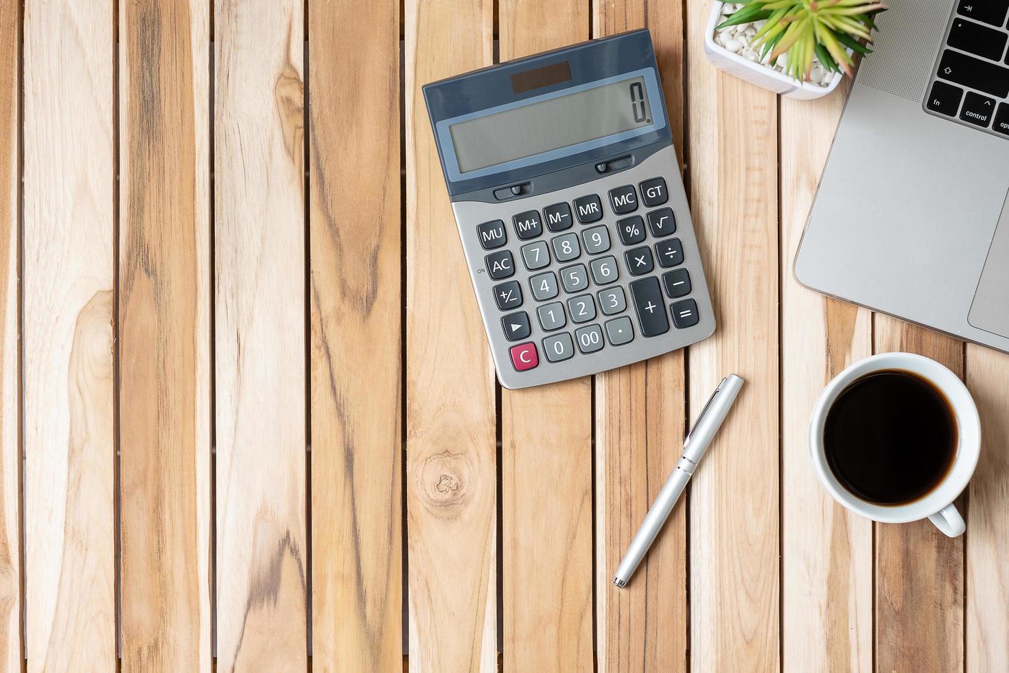 Top view Office desk with calculator, pen, computer laptop, plant pot and coffee cup on wood table background. workspace or home office with copy space for text concept photo