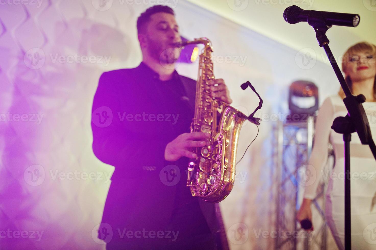 Musicial music live band performing on a stage with different lights. Saxophonist plays. photo