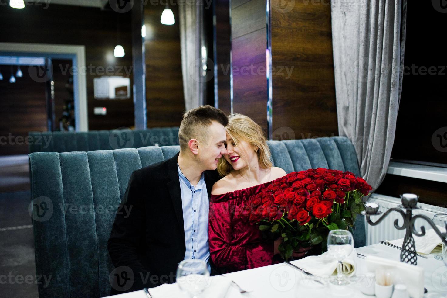 pareja amorosa enamorada en el restaurante con un gran ramo de 101 rosas. foto