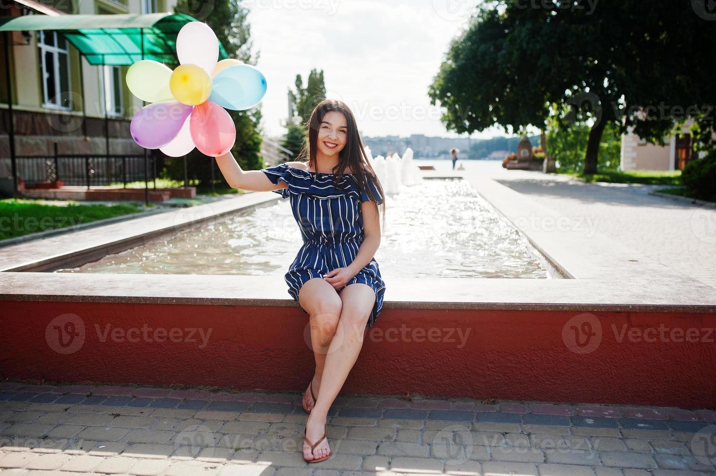 Gorgeous brunette girl at street of city with balloons at hands. photo