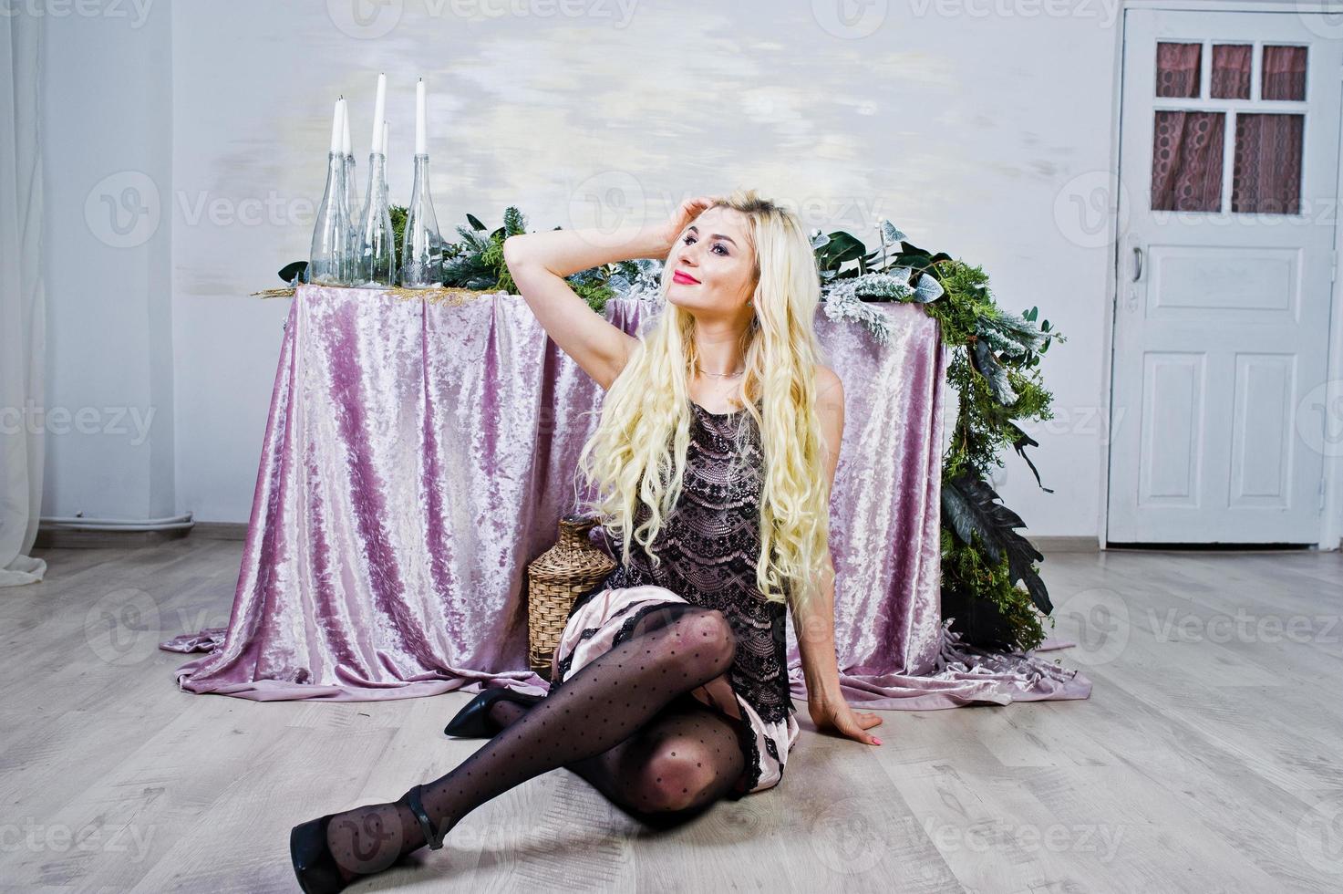 Elegante blonde girl wear on black dress sitting against table with christmas decoration. photo