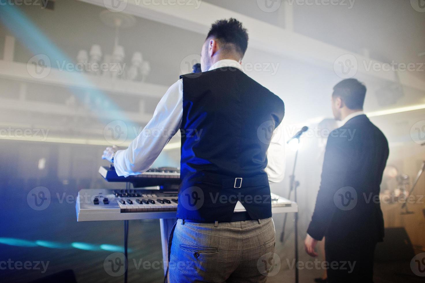 Musicial music live band performing on a stage with different lights. Keyboardist play. photo