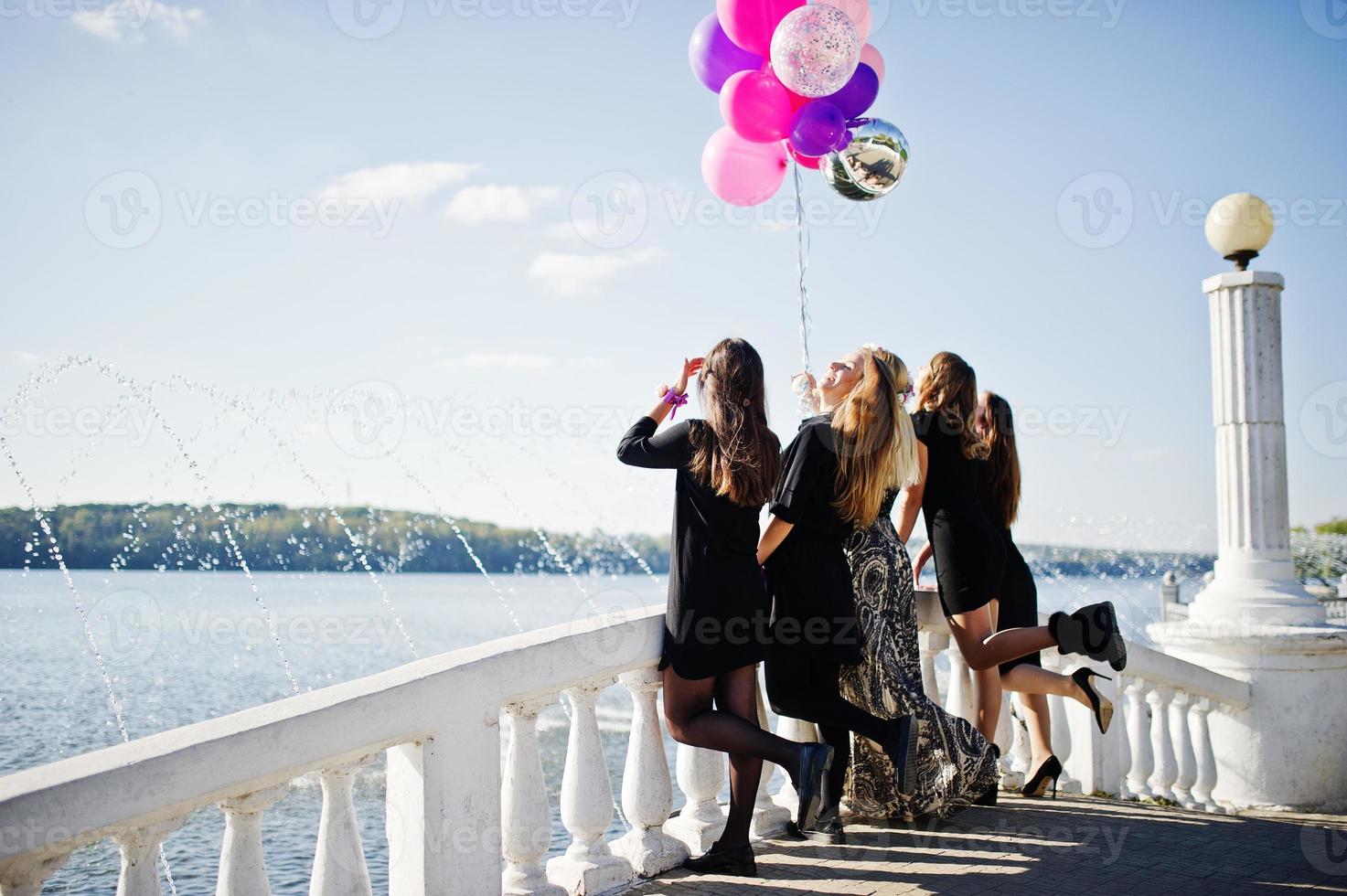 Back of five girls wear on black with balloons at hen party against lake. photo