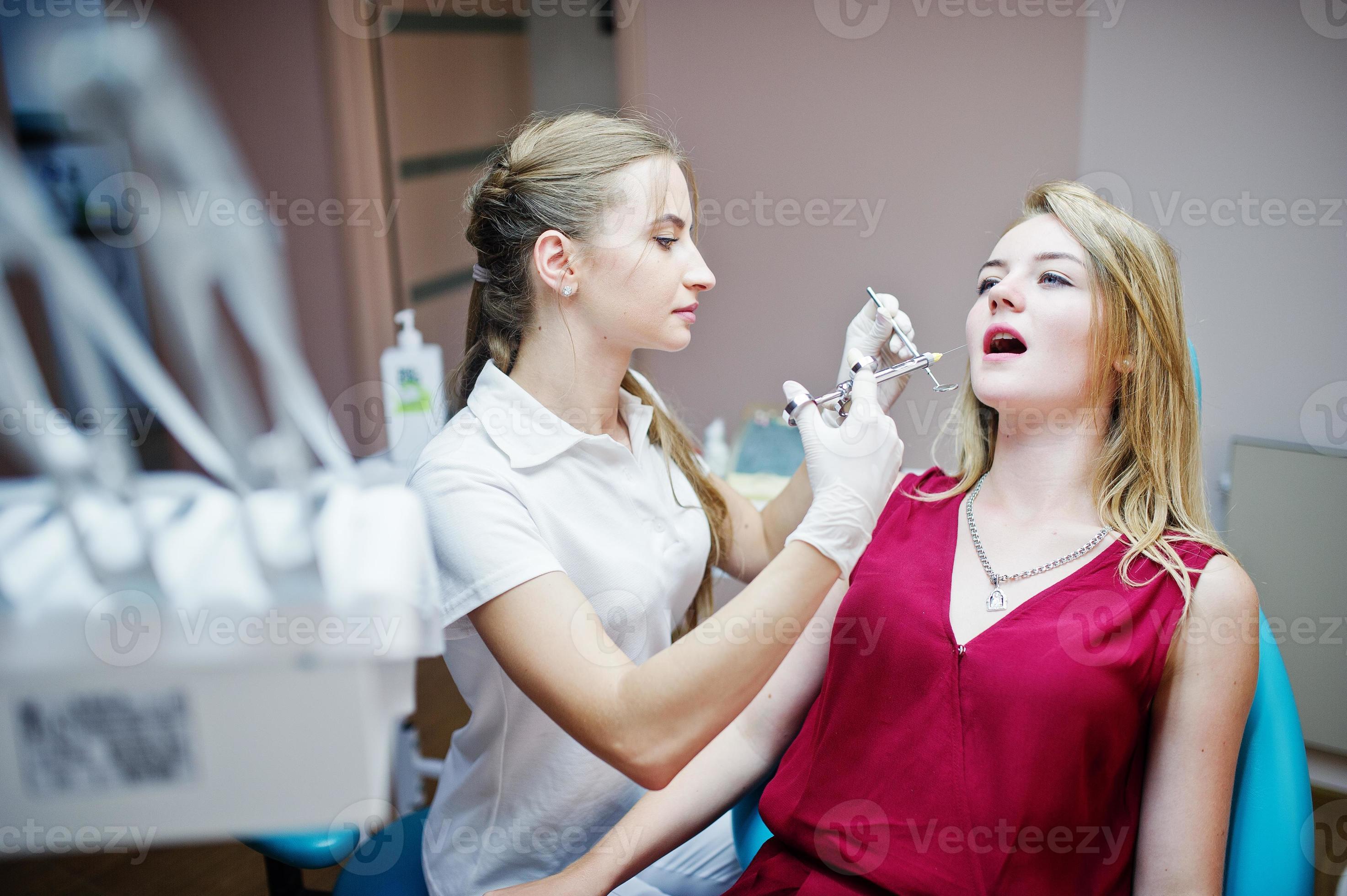Attractive female orthodontist injecting anesthesia to her patient in a