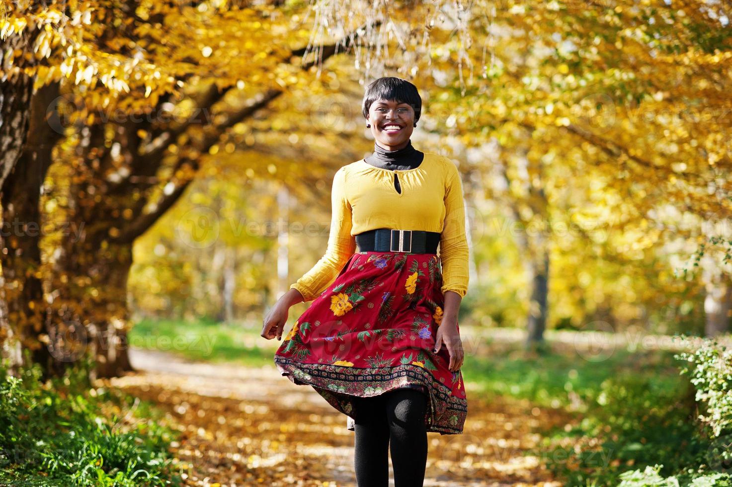 African american girl at yellow and red dress at golden autumn fall park. photo