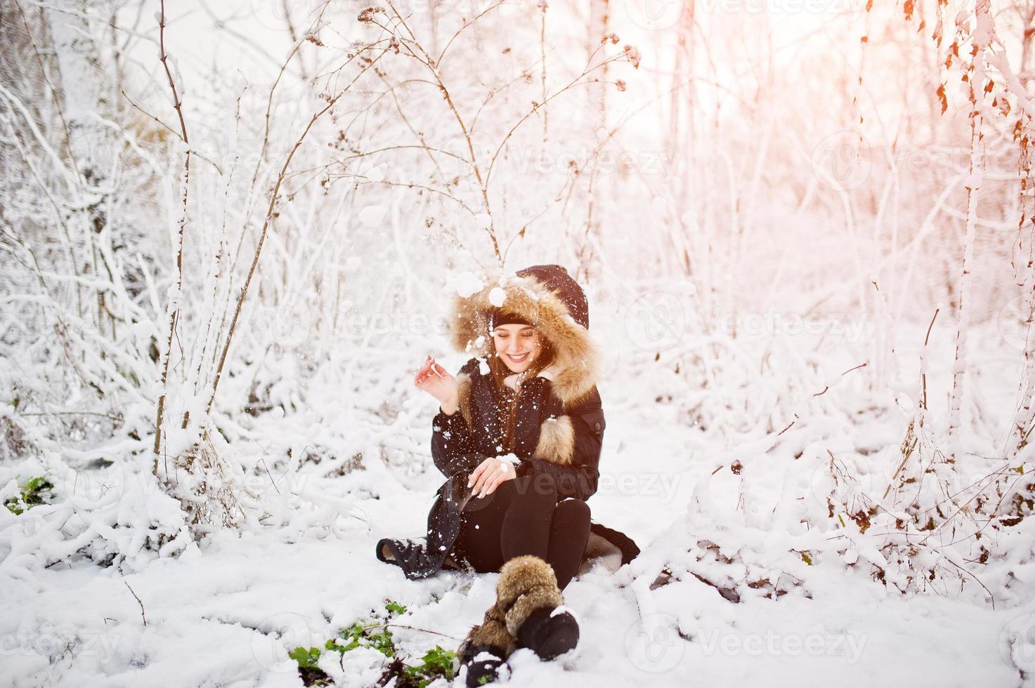 Beautiful brunette girl in winter warm clothing. Model on winter jacket and black hat. photo