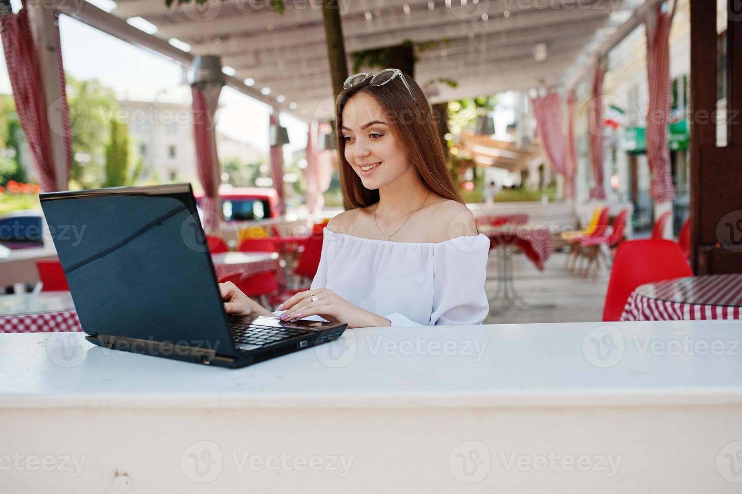 retrato de una fuerte y exitosa mujer de negocios independiente que usa ropa informal elegante y gafas que trabajan en una laptop en un café. foto