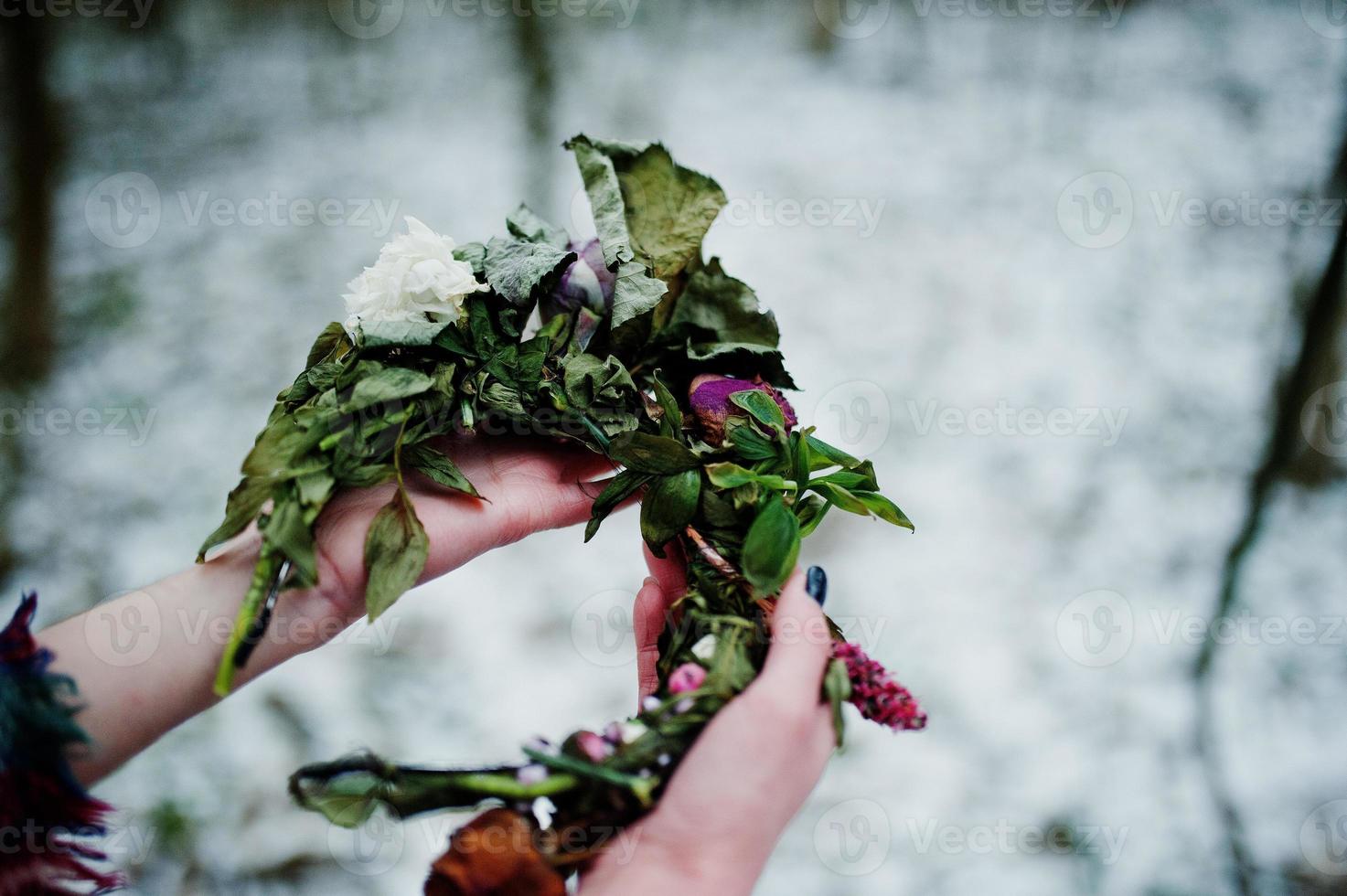 Ggirl holding wreath on hands at snowy forest in winter day. photo