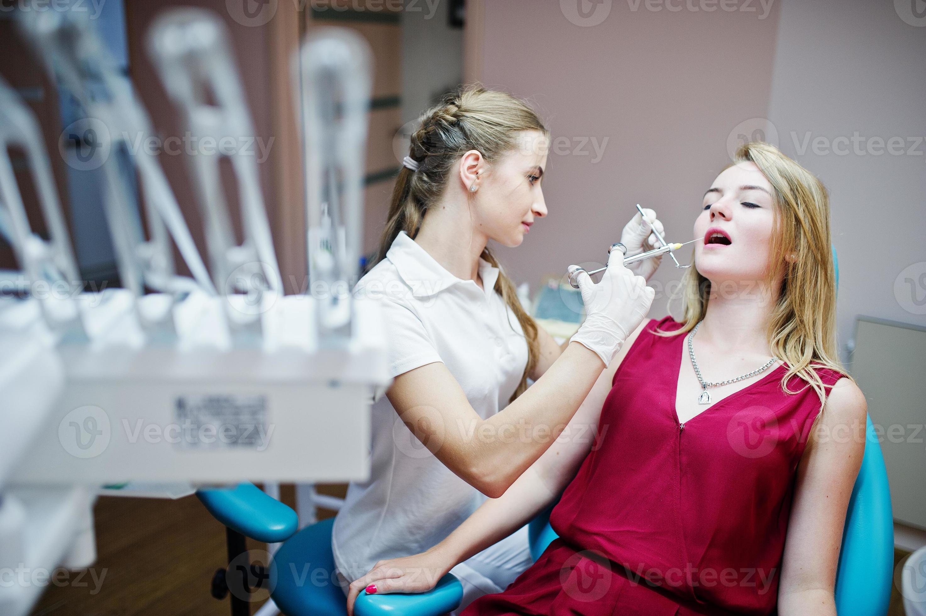 Attractive female orthodontist injecting anesthesia to her patient in a