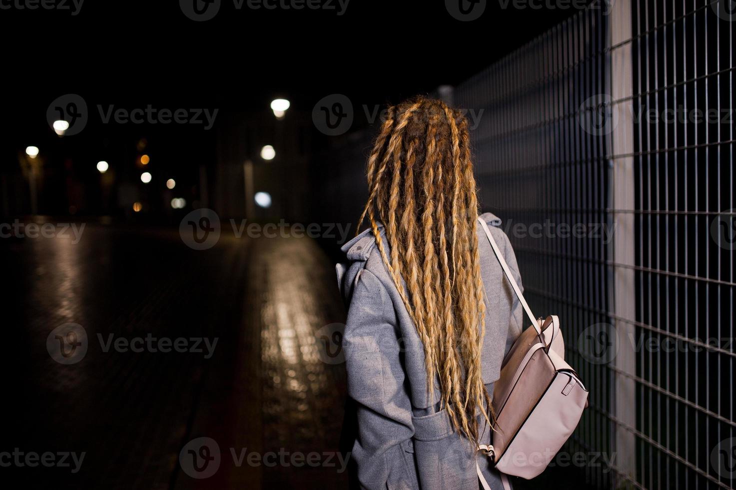 chica con rastas caminando por la calle de noche de la ciudad. foto