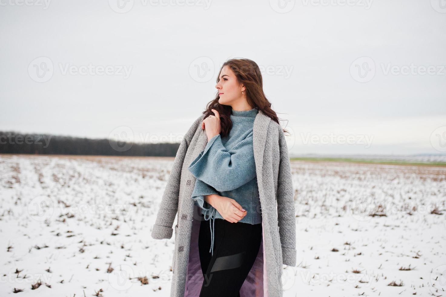 Gentle girl in gray coat against snow landscape. photo