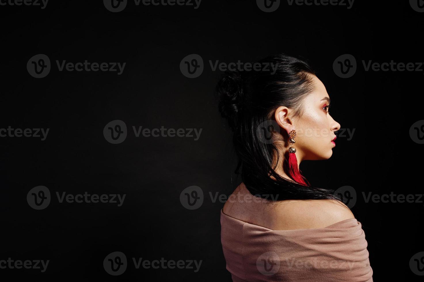 Retrato de estudio de niña morena de peinado trasero sobre fondo negro. foto