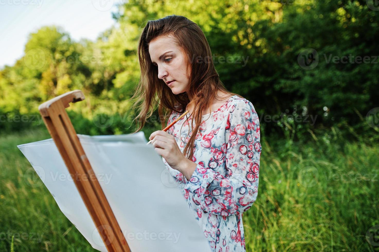 retrato de una joven atractiva con un vestido largo pintando con acuarela en la naturaleza. foto
