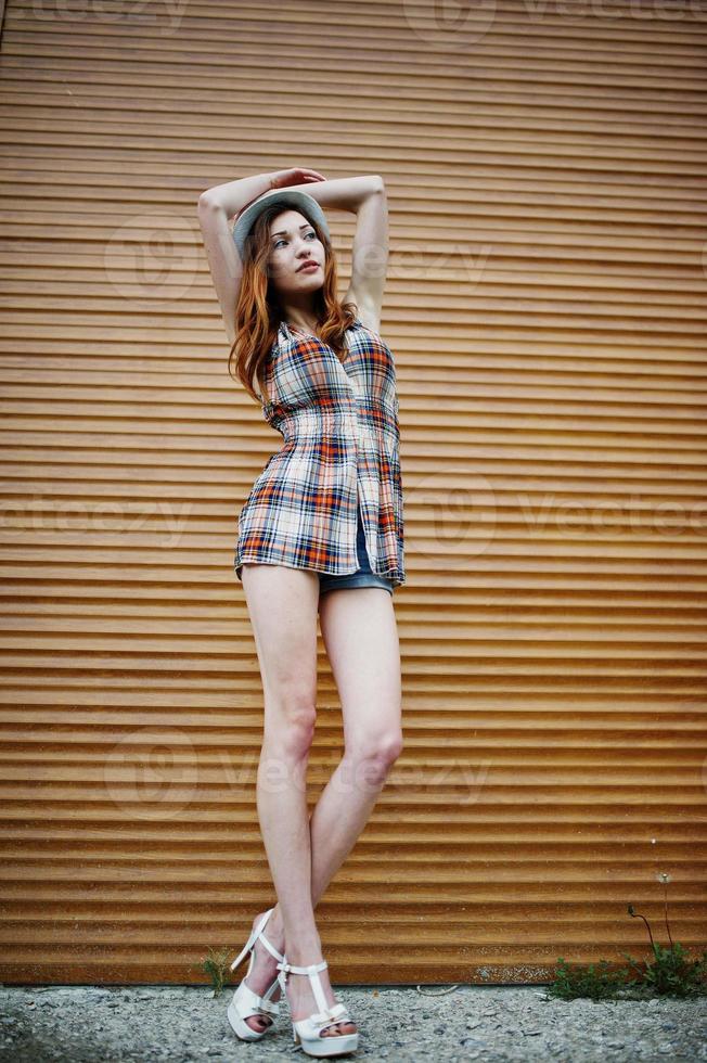 Amazing long legs with hig heels girl wear on hat against shutter. photo