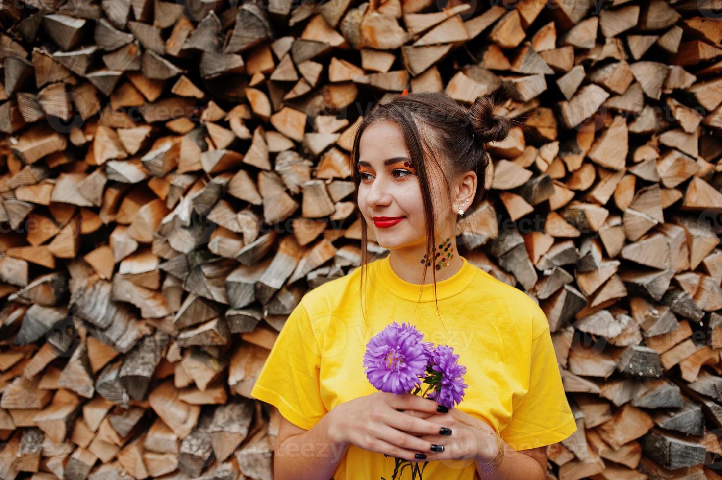 Girl in yellow shirt with violet aster flowers at hands. photo