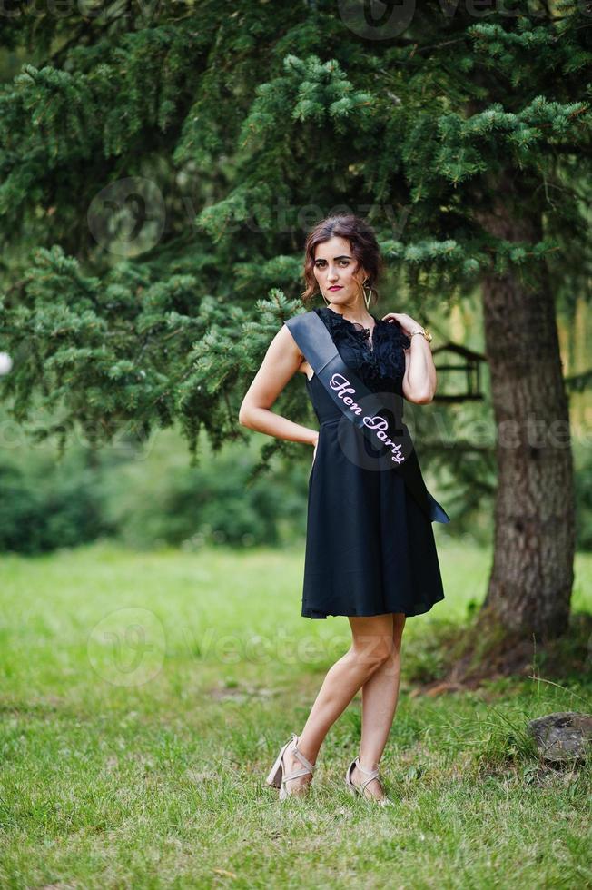 Portrait of gorgeous girl wear on black at hen party, posed at park. photo