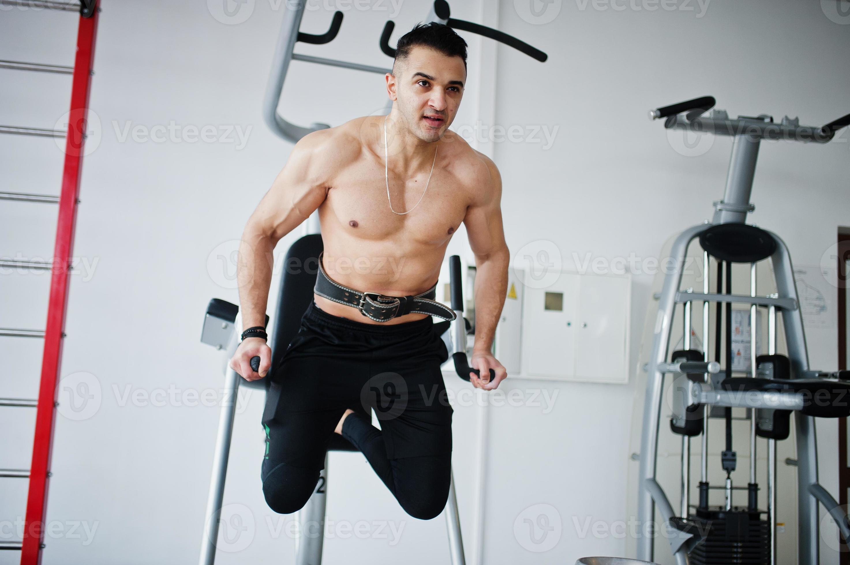 Muscular arab man training in modern gym. Fitness arabian men with naked torso doing exercises