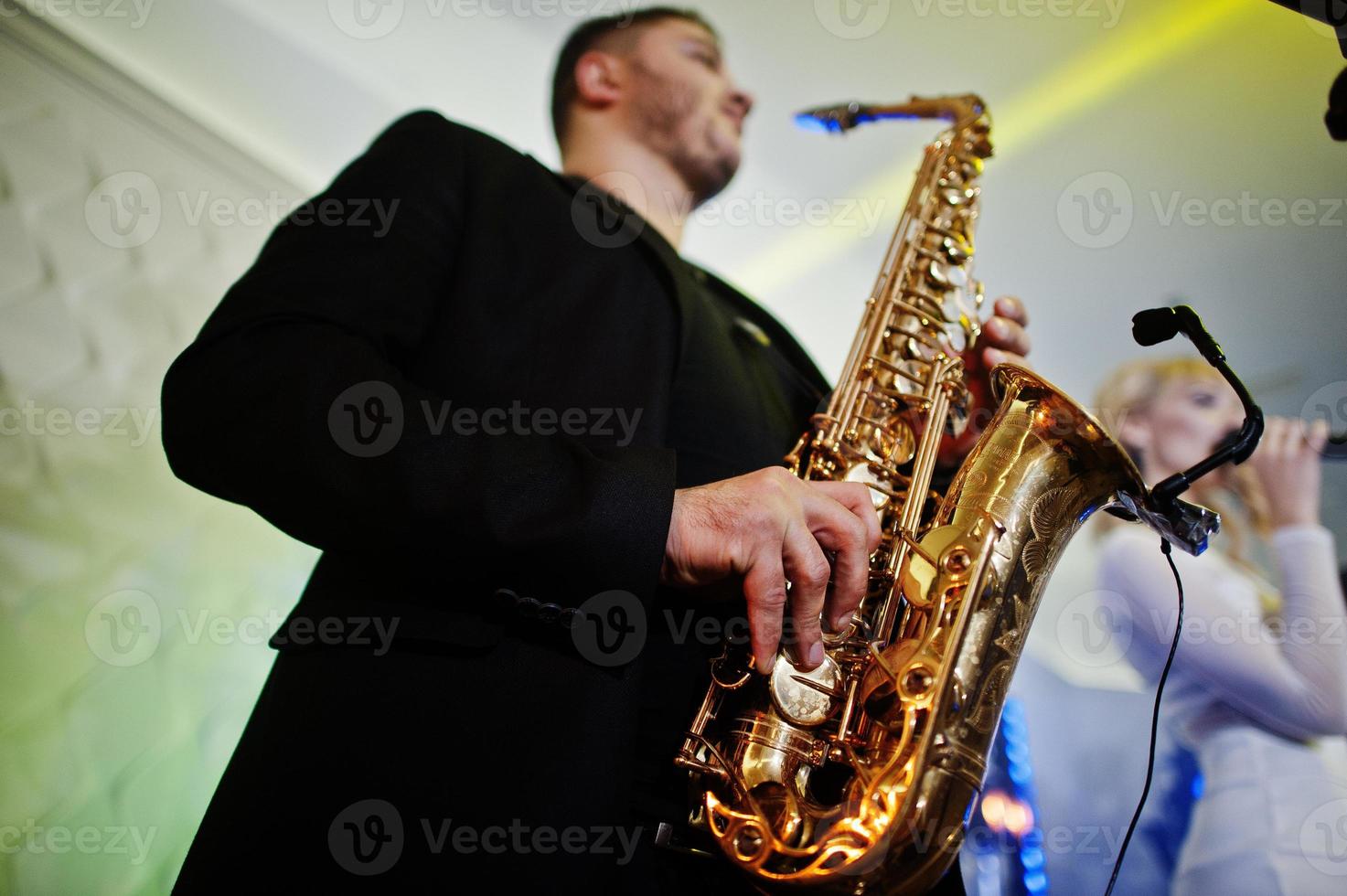 Musicial music live band performing on a stage with different lights. Saxophonist plays. photo