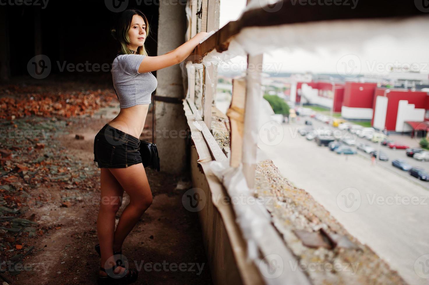 Girl wear on shorts at abadoned factoty with brick walls. photo