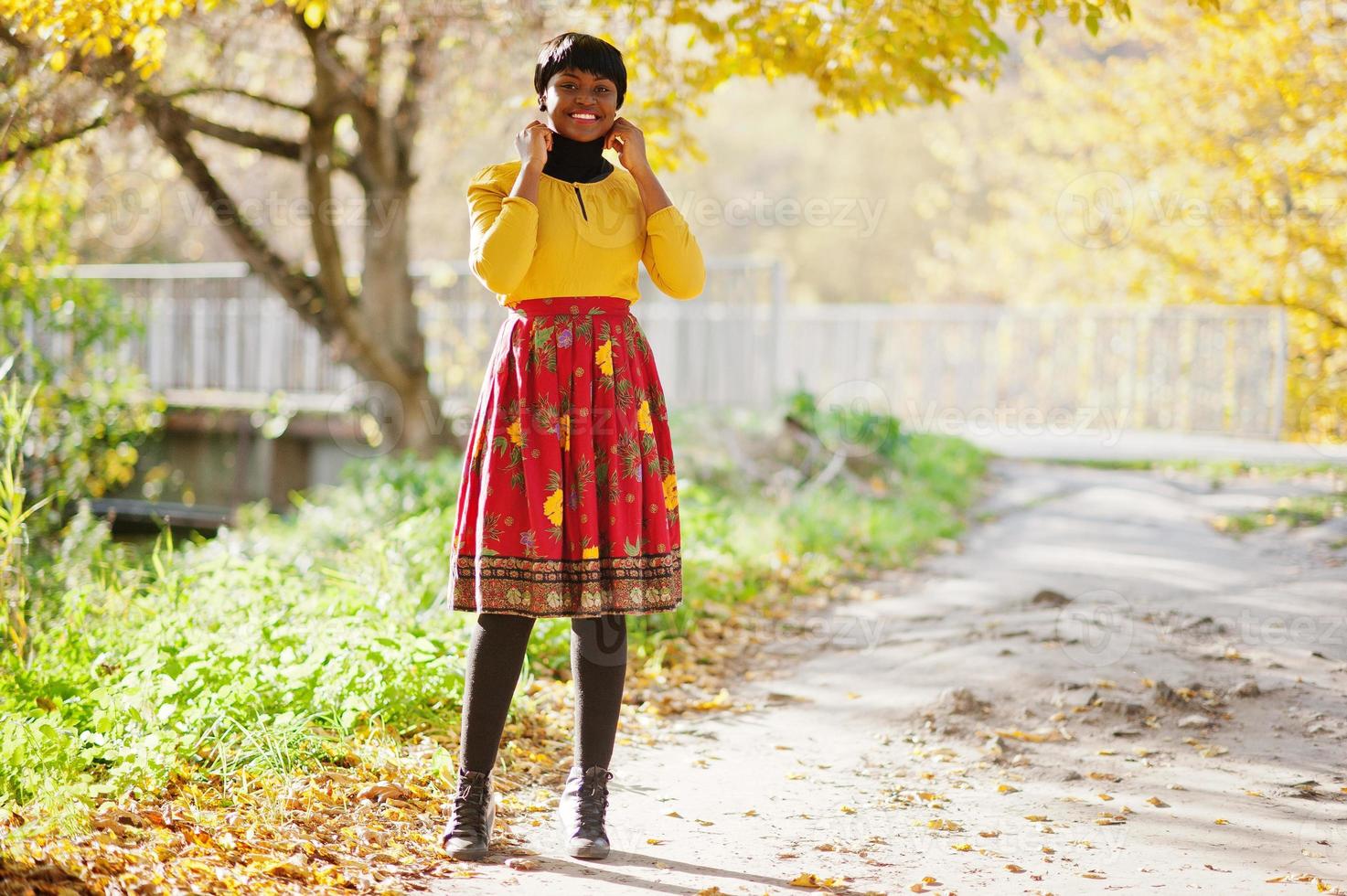 African american girl at yellow and red dress at golden autumn fall park. photo