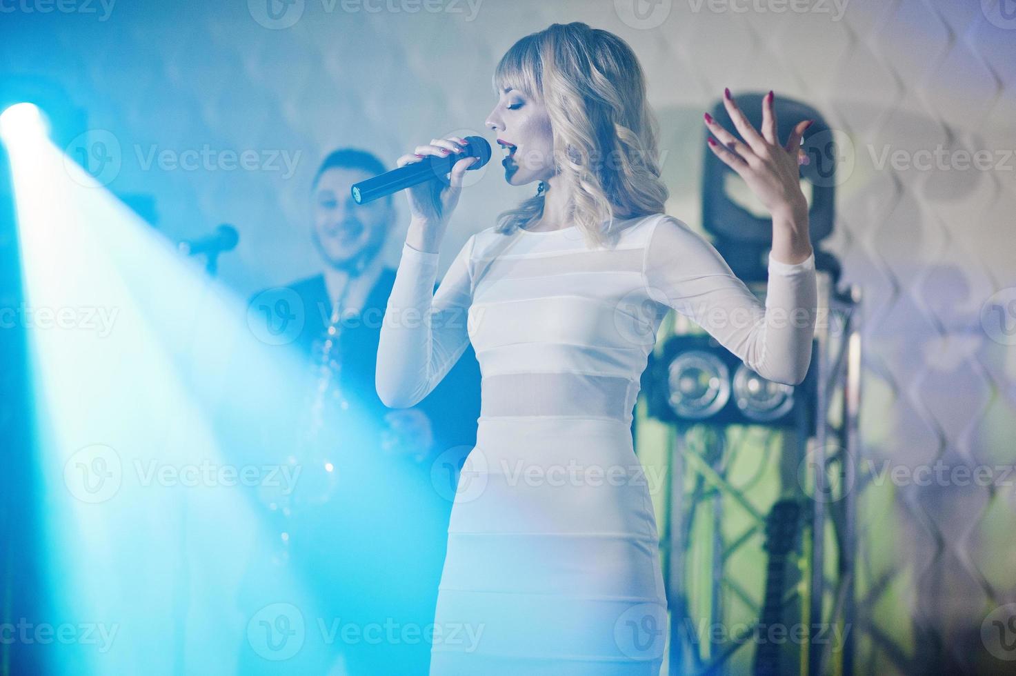 Musicial music live band performing on a stage with different lights. Beautiful blonde vocal singer girl. photo